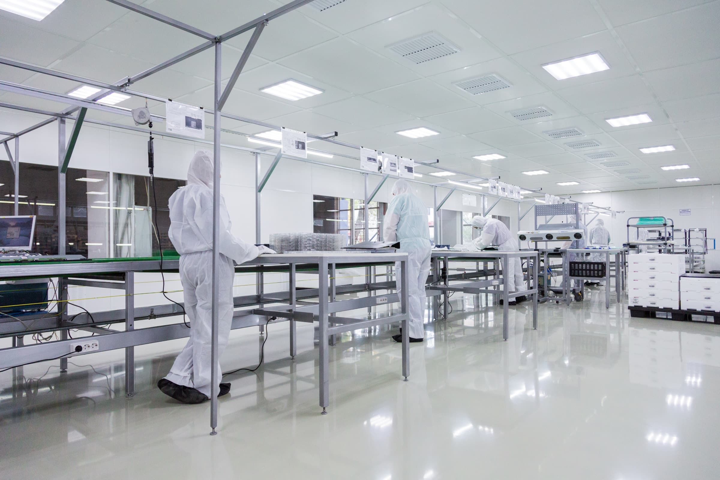 Cleanroom with technicians in protective suits handling battery cells